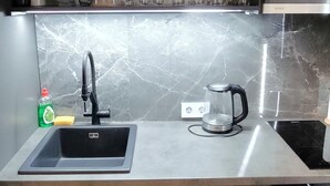 A modern kitchen with a stainless steel sink, a coffee maker, and a built-in oven.
