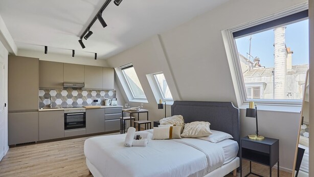 A modern bedroom with a large bed, a bedside table, and a nightstand. There is a window with a view of buildings outside. - Sublim Studio Beaubourg/le Marais (Paris)