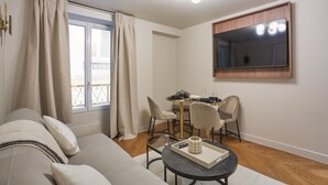 Un salon moderne comprenant un canapé, une table à manger avec des chaises, une petite table basse et un grand miroir accroché au mur.