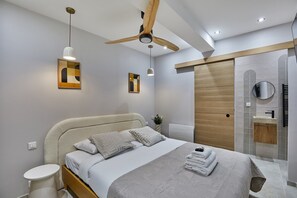 Un dormitorio moderno con una cama grande, un ventilador de techo y cabina de ducha integrada.