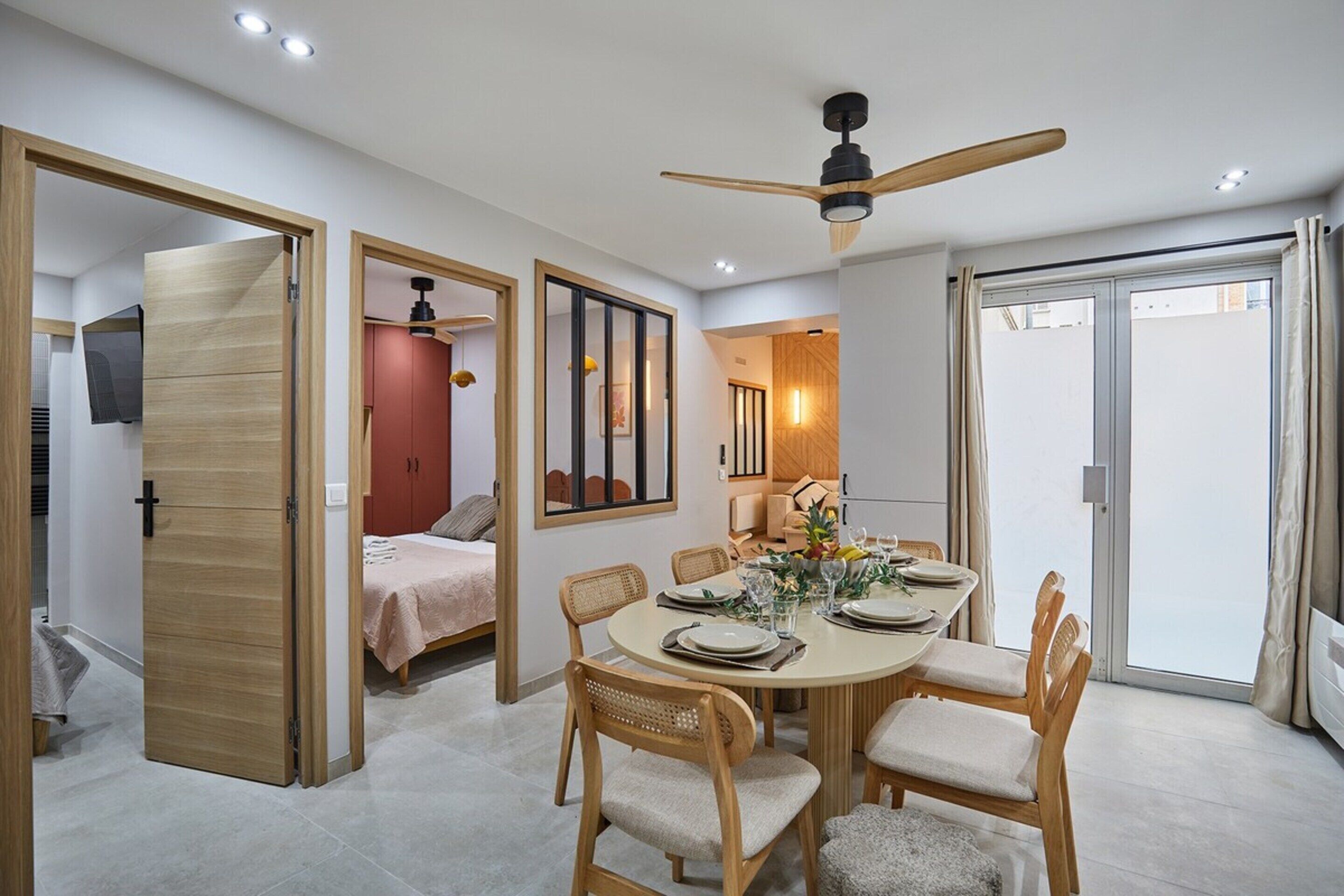 A modern dining area with a round table, wooden chairs, and a ceiling fan.