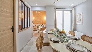 A dining area with a table set for four, a ceiling fan, and a view of a living room with a sofa and a coffee table. - Sublime Flat Paris Gare de Lyon/bois de Vincennes (Paris)