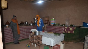 A rustic kitchen with a table set for a meal, a hanging basket, and various cooking utensils. - Camp Mbark authentic (M'Hamid El Ghizlane)