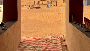 A room with a view of a desert landscape, featuring a wooden ceiling and a striped rug on the floor. - Camp Mbark authentic (M'Hamid El Ghizlane)