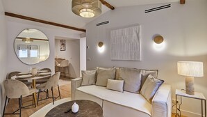 A modern living room with a sofa, a coffee table, a dining area with chairs and a table, and a large mirror. - Superb Apartment in the Heart of Paris (Paris)