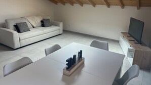 Una sala de estar moderna con un sofá, una mesa de comedor y un televisor.