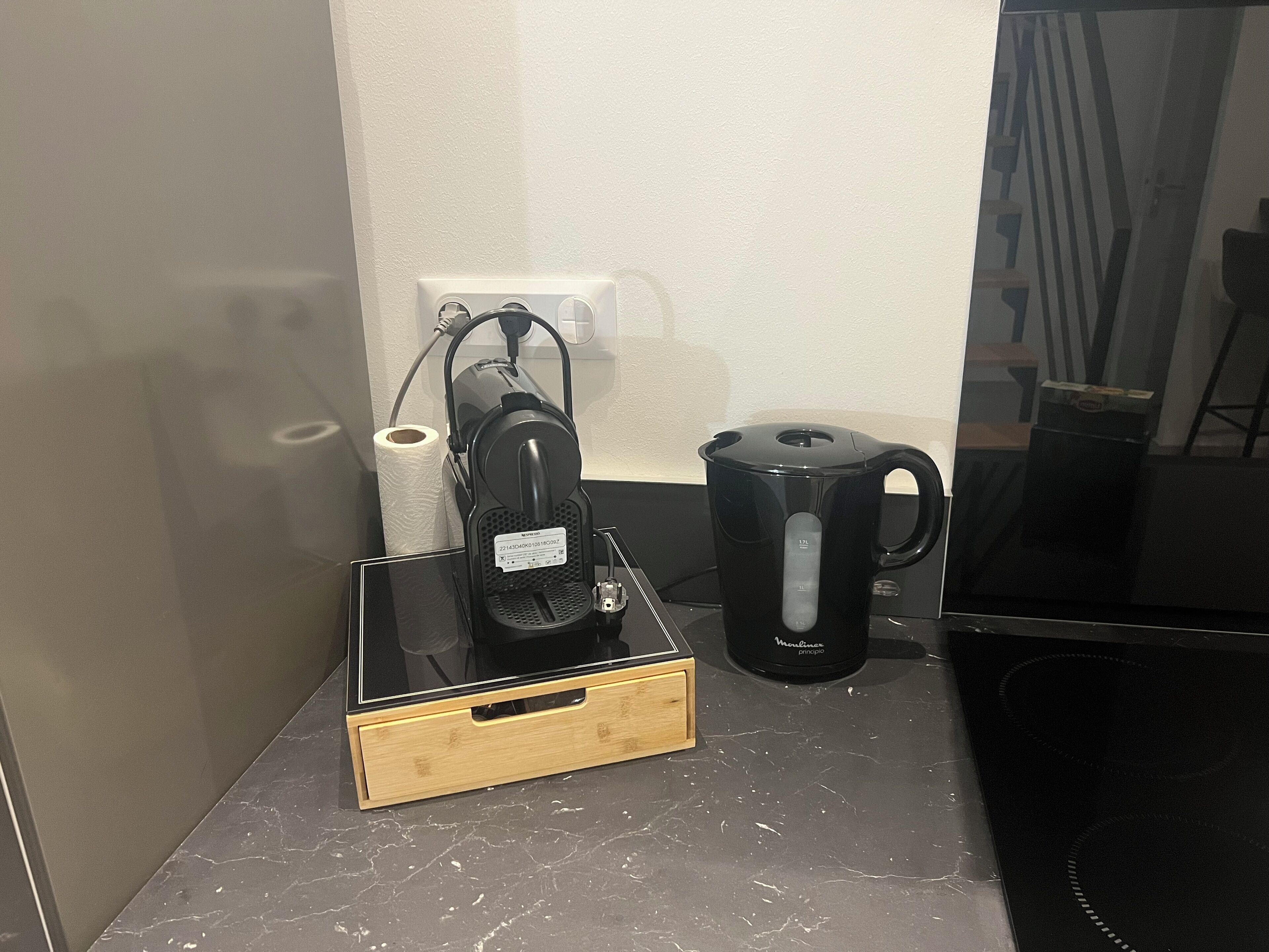 En køkkenbordplade med kaffemaskine, elkedel og en æske.
