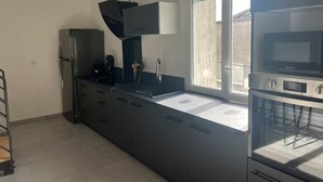 Una cocina moderna con encimera negra, electrodomésticos de acero inoxidable y ventana con vistas.