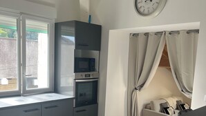 Una cocina moderna con microondas, horno y un reloj en la pared.