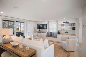 A modern living room with a sofa, armchairs, a coffee table, and a TV. - Walk to beach, private patio! (Eastham)