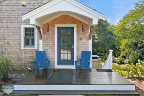 A house with a porch, two blue chairs, a black door, and a number 27 on the wall. - Walk to beach, private patio! (Eastham)