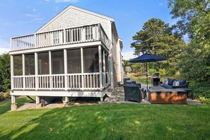 A house with a large screened porch, a deck, and a patio area with outdoor furniture.