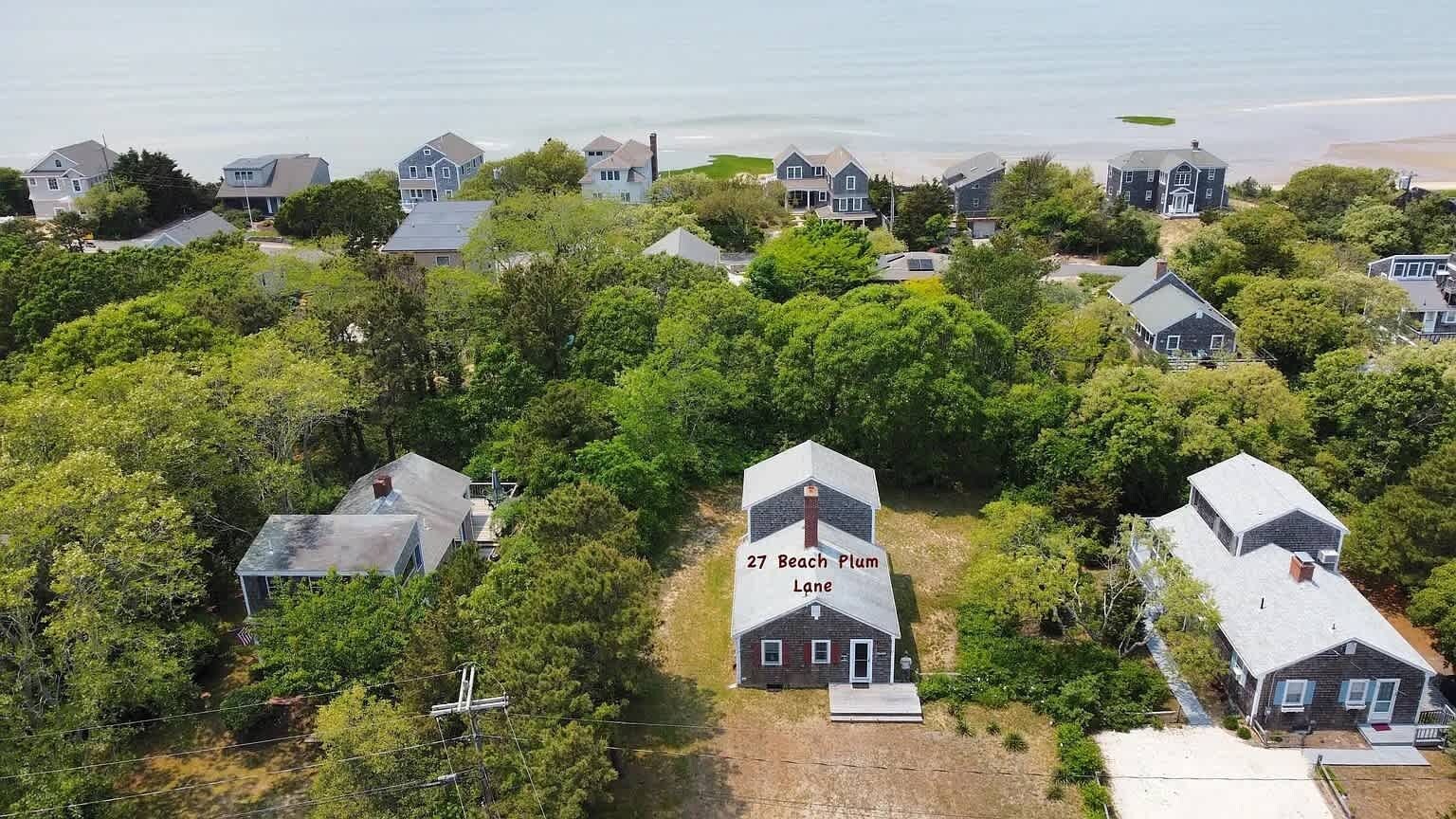 A residential area with houses surrounded by trees, including a house labeled "27 Beach Plum Lane".
