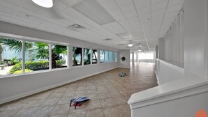 Um corredor amplo com grandes janelas, soalho em azulejos e um banco.