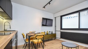 A modern kitchen with a dining area, a TV mounted on the wall, and a large window with a view of buildings. - Welcoming Apartment - 1br/4p - Arc de Triomphe (Paris)