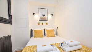 A hotel room with a bed, two pillows, a framed picture on the wall, and a radiator. - Welcoming Apartment - 1br/4p - Arc de Triomphe (Paris)
