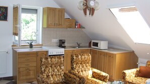 A compact kitchen with wooden cabinets, a microwave, and a coffee maker. There are two patterned armchairs and a small table with a vase. - Well-kept apartment in Fonyod for 4-5 people within walking distance of the lake - new air conditioning (Fonyód)