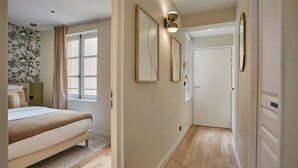 A bedroom with a bed, a window, and a hallway leading to a door. - Sublim Apartement in the Center of Paris/le Marais (Paris)