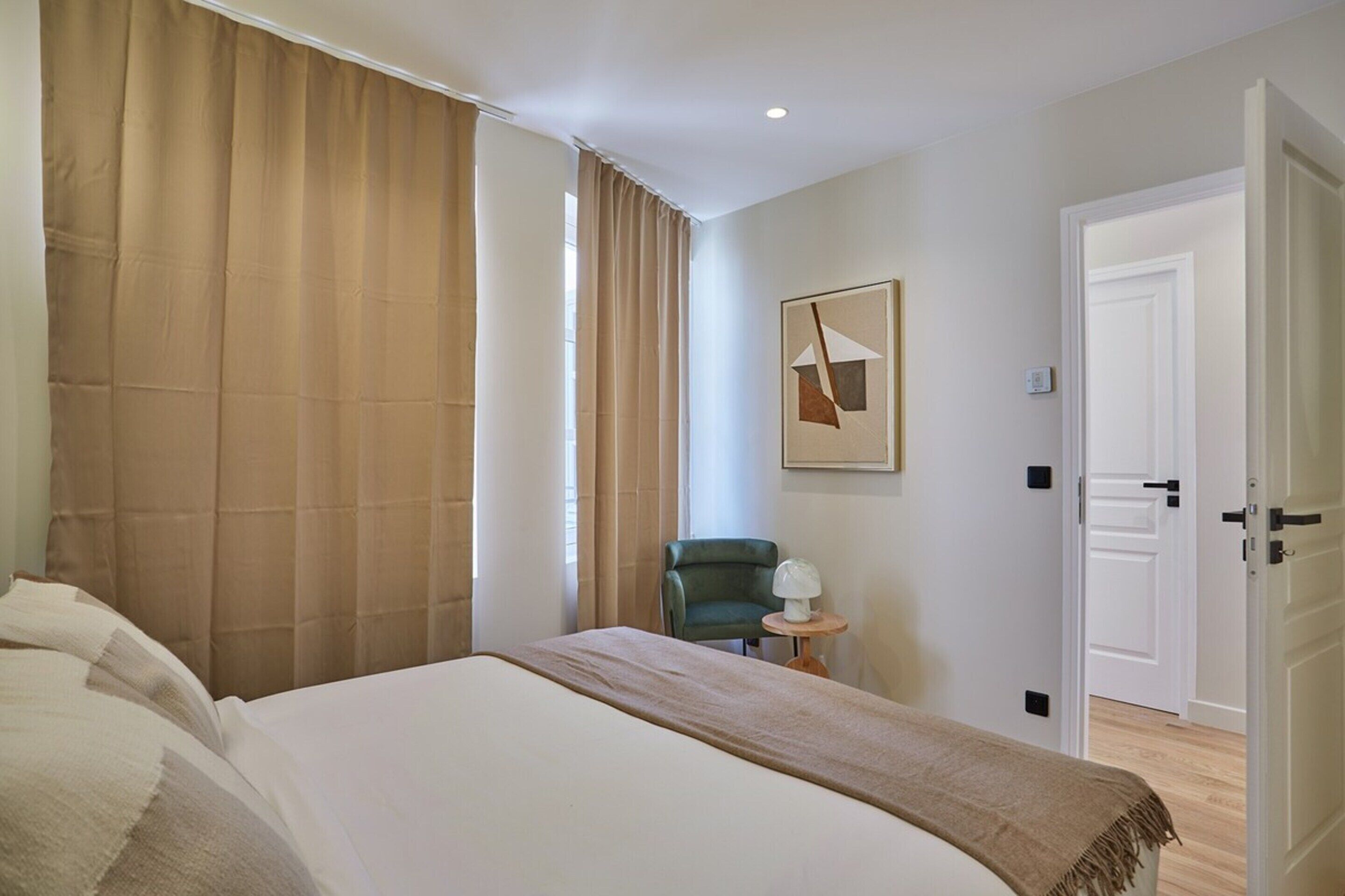 Une chambre d’hôtel avec un lit, une chaise, une lampe et une porte.