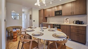 A modern kitchen with wooden cabinets, a white dining table set for four, and a pendant light. - Sublim Apartement in the Center of Paris/le Marais (Paris)