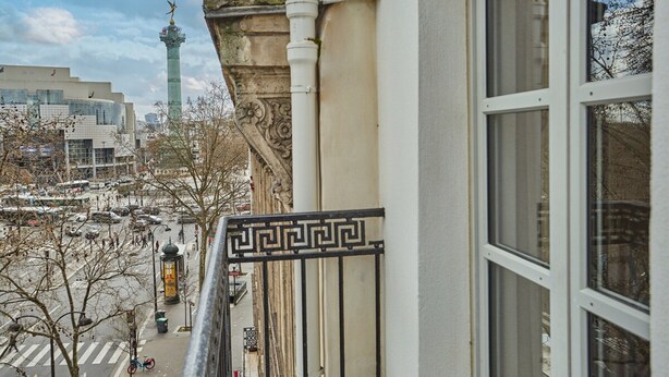 A view from a window overlooking a city street with a prominent tower in the background. - Sublim Apartement in the Center of Paris/le Marais (Paris)