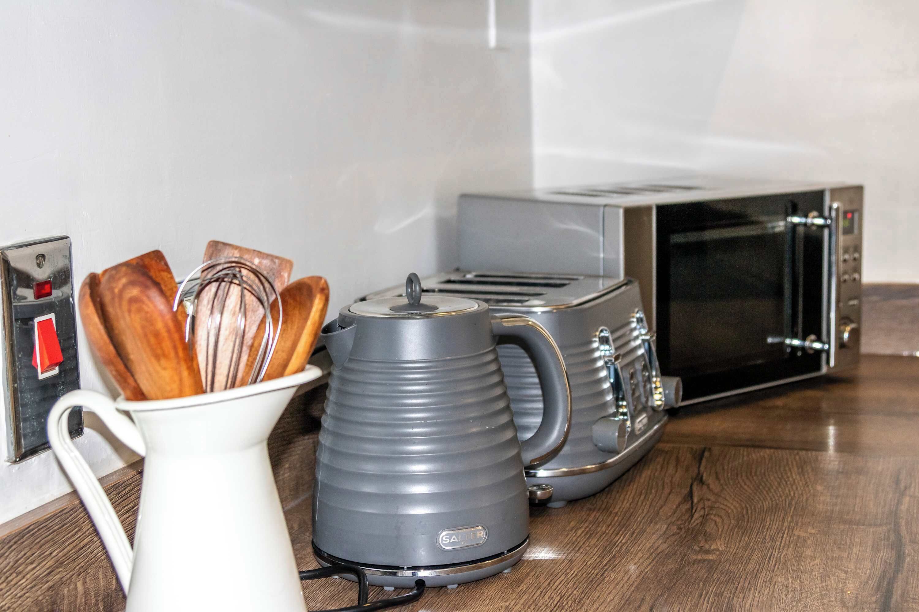 A kitchen with a toaster, a kettle, and a microwave.