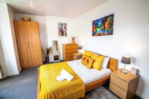 Quarto com cama, mesas de cabeceira, guarda-roupa e obras de arte nas paredes.