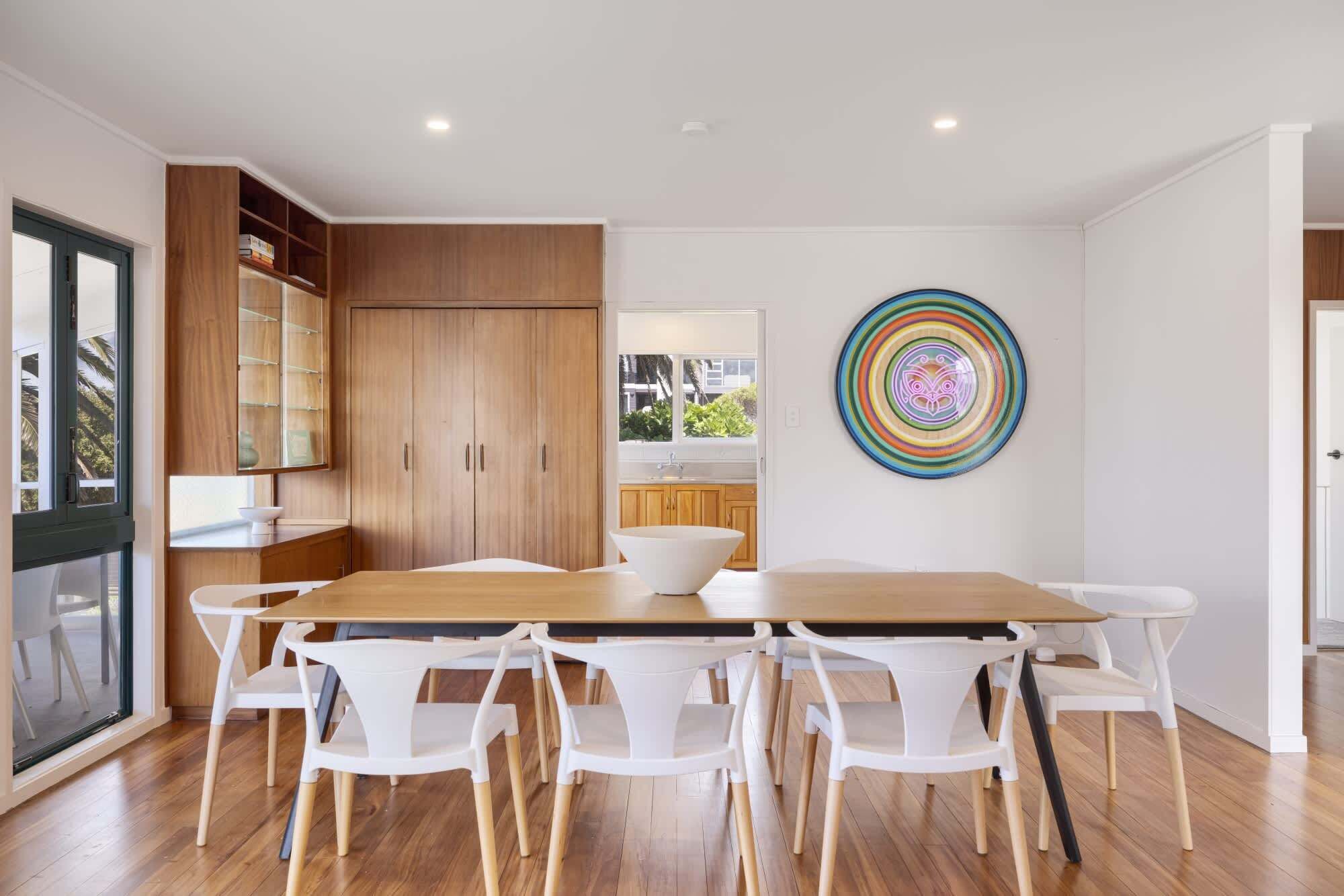 A modern kitchen with wooden cabinets, a large island, and a colorful abstract art piece on the wall.