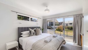 A bedroom with a bed, bedside table, and a view of the outside.