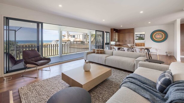 A spacious living area with a large sliding glass door leading to a balcony with a beach view.
