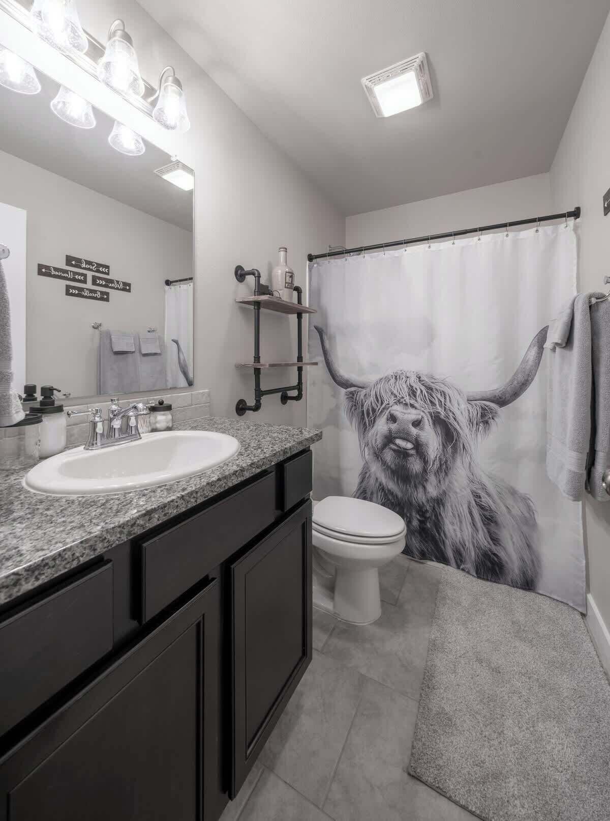 A bathroom with a sink, toilet, and a large mirror.