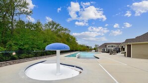 A swimming pool area with a blue dome structure, a covered patio, and a house in the background. - Beautiful townhome with community pool, shuttle to Bethany, and more! (Millville)