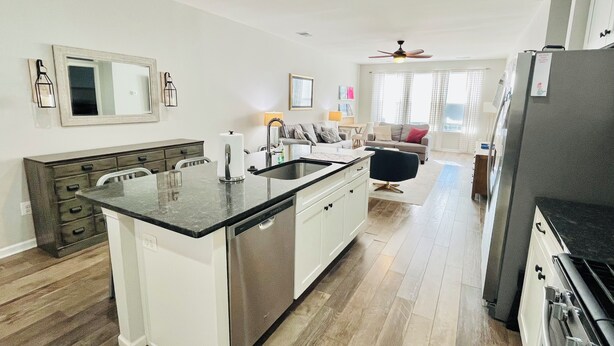 A modern kitchen with a central island, white cabinetry, and a stainless steel dishwasher. - Beautiful townhome with community pool, shuttle to Bethany, and more! (Millville)