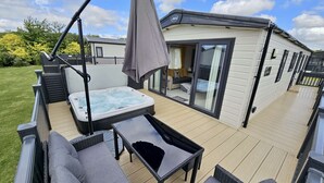 A deck with a hot tub, outdoor seating, and a covered area. - Daisy, A Hot Tub Home, Also Dog Friendly (Hoburne Holiday Park)