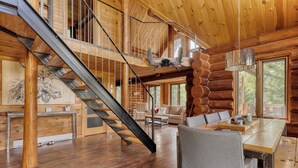 A spacious log cabin interior with a central staircase, a dining area, and a cozy living room. - Spa and Great Comfort | Le Bo Bois Rond (Saint-Michel-des-Saints)