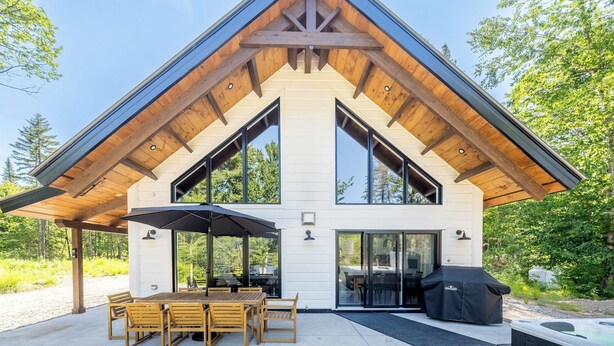 A modern house with a large patio, a dining area, and a hot tub. - Spa, Steam room and Lake | Le Stuga (Lac-aux-Sables)