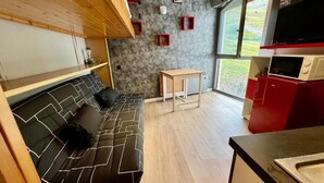 A compact living space with a sofa, a small table, and a kitchenette area. - Orcieres - Studio at the foot of the slopes (Orcières)