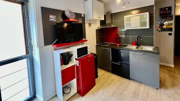 A compact kitchen with modern appliances, a microwave, a red refrigerator, and a dishwasher. - Orcieres - Studio at the foot of the slopes (Orcières)