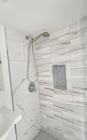 Ein Badezimmer mit Dusche, gefliesten Wänden und einem kleinen Fenster.