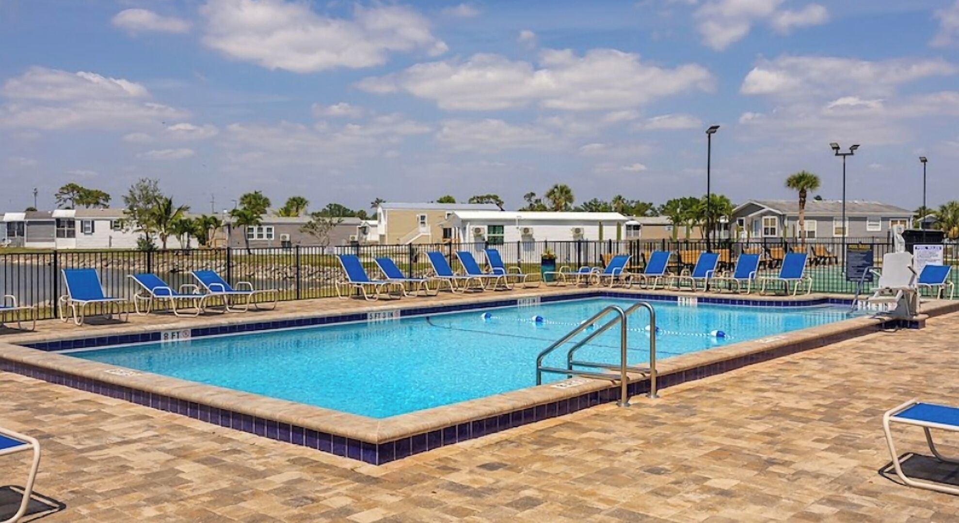 A swimming pool with blue lounge chairs and a tiled deck.