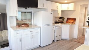 A compact kitchen with white cabinets, a built-in oven, and a refrigerator.