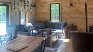 Uma sala de estar aconchegante com uma parede de madeira, um sofá, uma mesa de centro e uma mesa de jantar com cadeiras.
