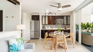 Una cocina moderna con armarios oscuros, electrodomésticos de acero inoxidable y un comedor con sillas de madera y una mesa.