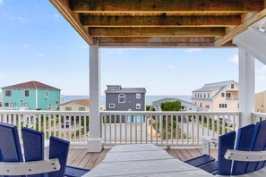 A covered deck with a view of beach houses and the ocean.