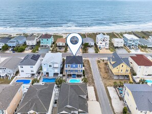 Luchtbeeld van een kustwoongebied met huizen, een zwembad en een strand.