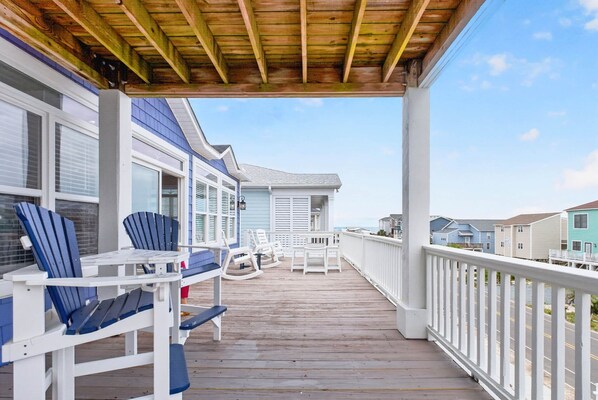A wooden deck with outdoor seating, a covered area, and a view of neighboring houses.