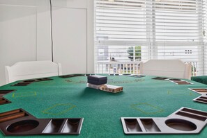 A blackjack table with chips, chairs, and a window with blinds.