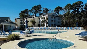 A pool area with blue lounge chairs and a circular pool. - River Oaks, Gorgeous 1BR condo (Myrtle Beach)
