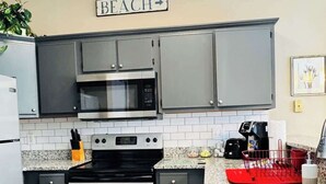 A modern kitchen with stainless steel appliances, a granite countertop, and a sign that reads "BEACH". - River Oaks, Gorgeous 1BR condo (Myrtle Beach)