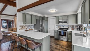 A modern kitchen with a central island, stainless steel appliances, and a dining area with bar stools. - New! Hot Tub ~ Foosball ~ Bonus Room ~ Dog Friendly ~ AC! (Bend)